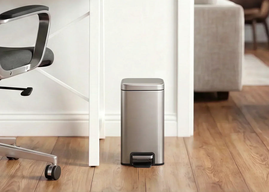 Compact stainless steel EKO step trash can beside a desk in an office workspace