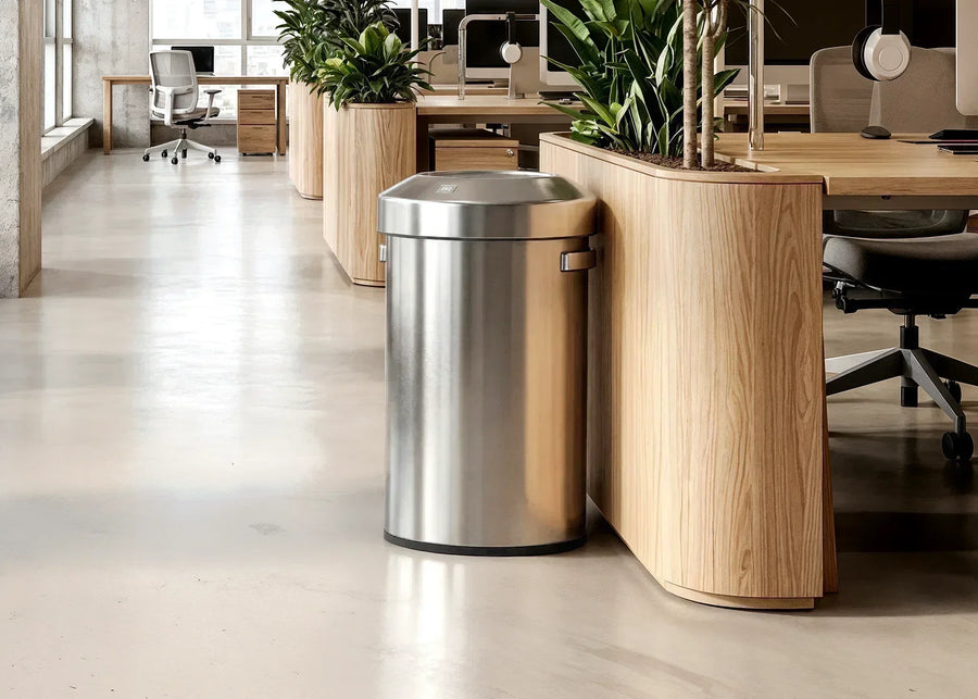 Stainless steel EKO semi-round trash can beside oak planter desks in a modern office