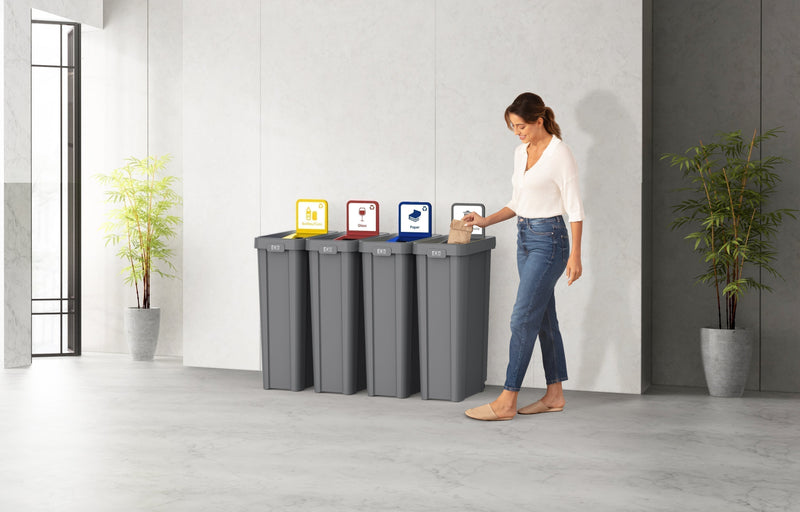 Employee sorting paper into a four-stream EKO recycling station with color-coded lids