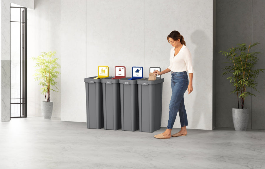 Employee sorting paper into a four-stream EKO recycling station with color-coded lids