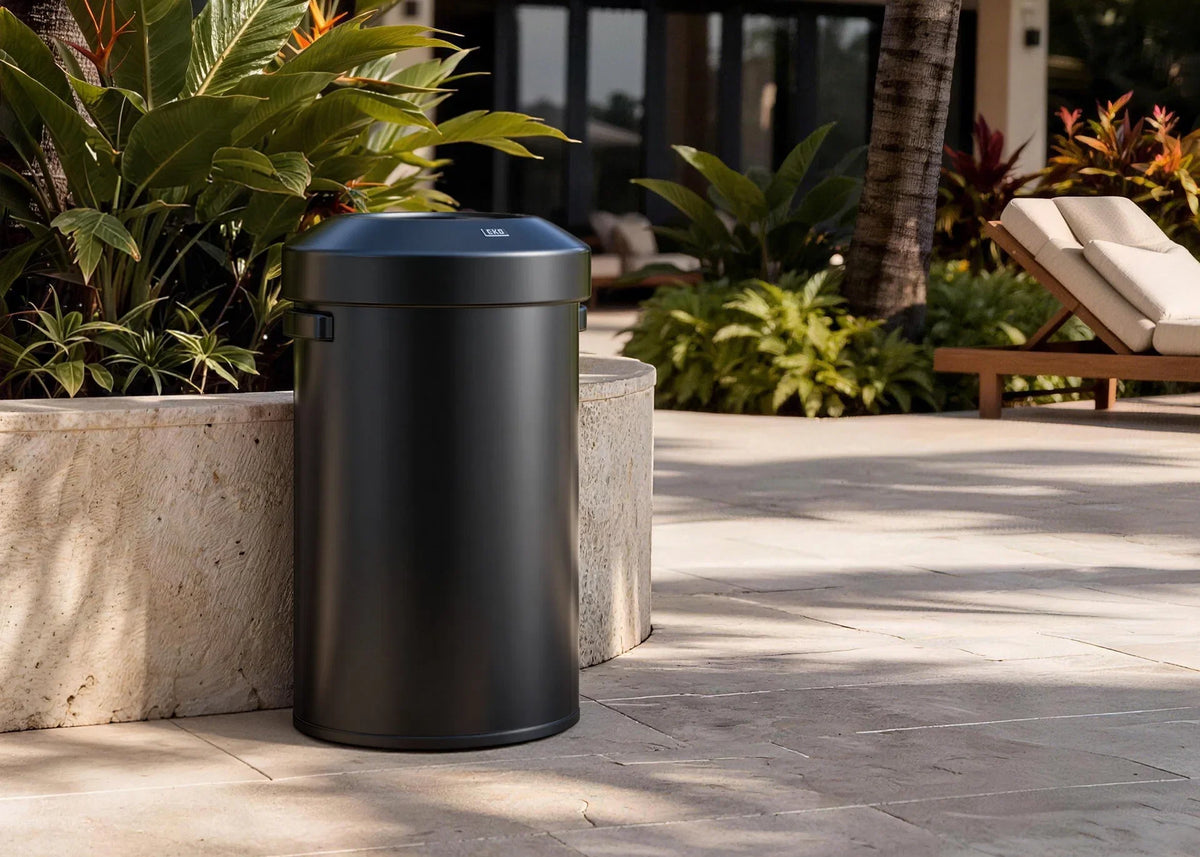 Black EKO commercial open-top trash can on a stone patio beside poolside loungers