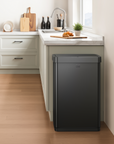 EKO trash can next to a modern kitchen counter, surrounded by light wood cabinetry and appliances.