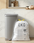A silver mini-fridge and a large white bag labeled EKO SENSIBLE ECO LIVING stand on a marble countertop in a kitchen, near wooden items and fresh bread.