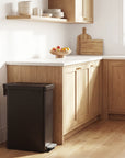 EKO black trash can in a kitchen setting with a countertop and cabinets.